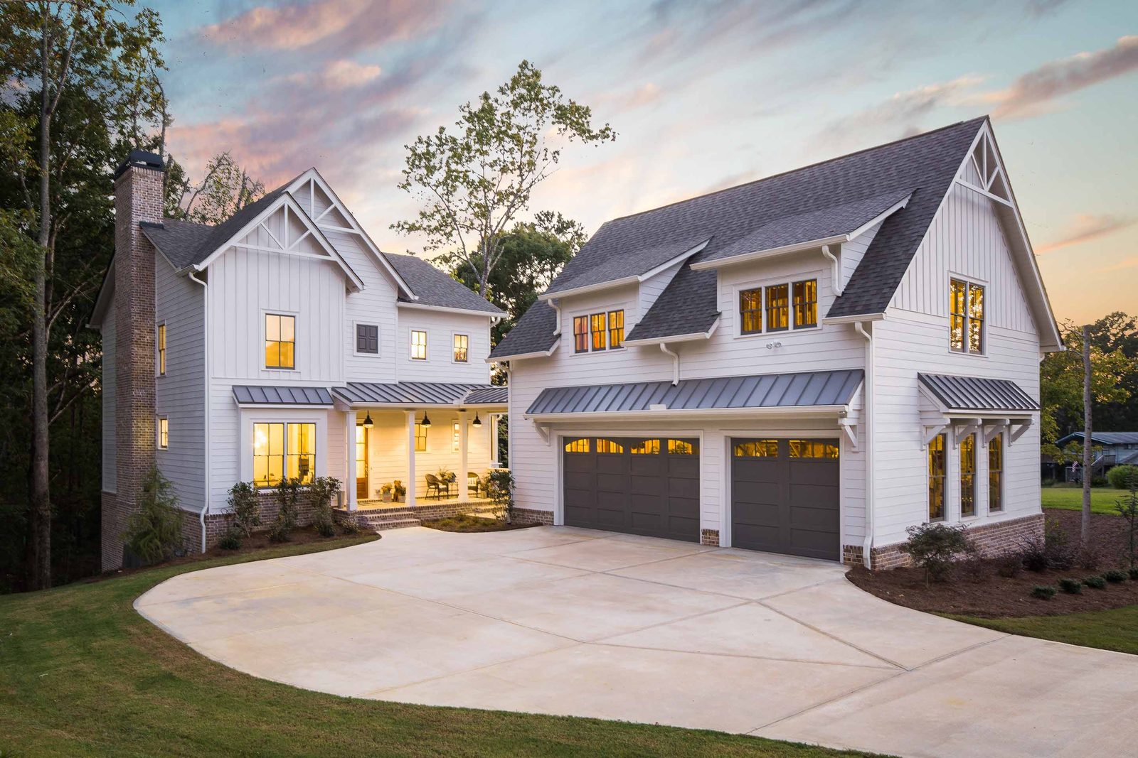 Front elevation at dusk with lit windows and circular drive — Austin Garner Rd, custom home built by Ironwood Construction Group